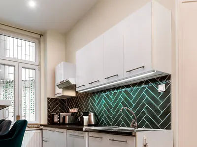 Bright kitchen with white cabinets and green backsplash at Doma Budapest